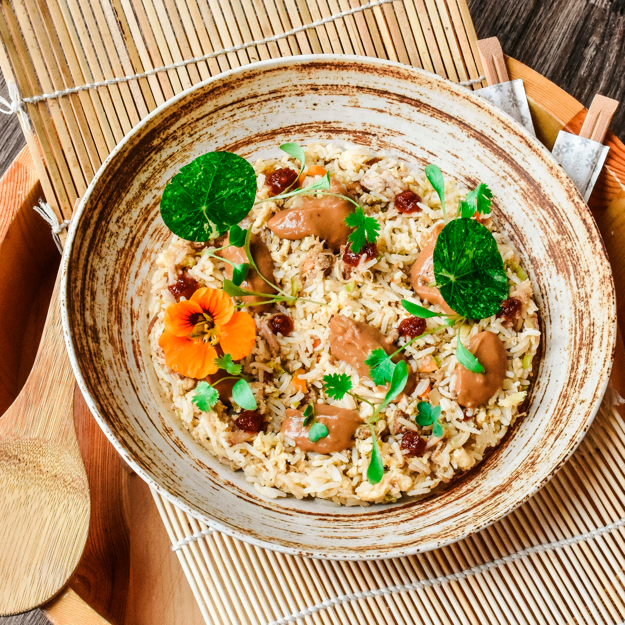 plato de comida con arroz, hierbas y flores sobre una mesa de madera